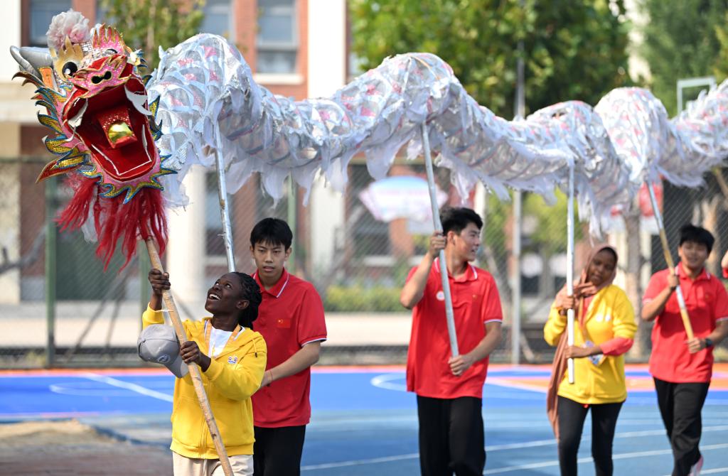 10月25日，“漢語橋”選手在天津霍元甲學(xué)校的操場上學(xué)習(xí)舞龍。新華社記者 李然 攝