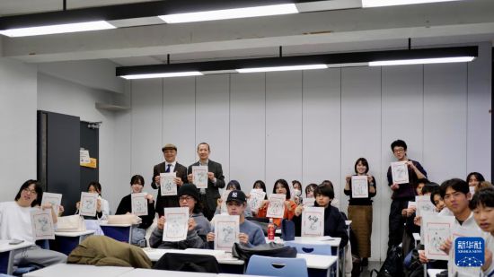 12月19日，在日本東京都的中央大學(xué)，學(xué)生們舉著自己制作的木版水印畫(huà)合影。新華社發(fā)